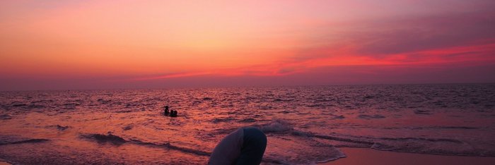 Magische Momente erleben Sie beim Yoga am langen Sandstrand während die untergehende Sonne alles um Sie herum in rosa Licht taucht