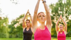 yoga-reisen-urlaub-meditation-wiese-gras-gruppe-vrksasana-baum Im Freien Yoga üben