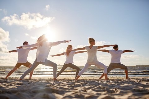 Üben Sie Yoga gemeinsam am Strand mit Gleichgesinnten