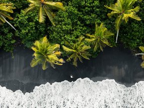 Schwarzer Strand mit Palmen auf Bali