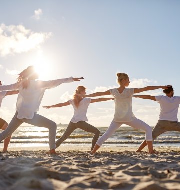 Üben Sie Yoga gemeinsam am Strand mit Gleichgesinnten